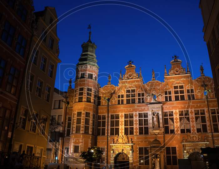 Gdansk, North Poland - August 13, 2020: Wide Angle Night Shot Of A Long Lane Street In Old Town Displaying Polish Architecture Against Clear Blue Night Sky
