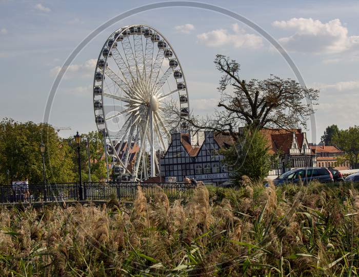 Gdansk, North Poland - August 15, 2020: Ferries Wheel Agaisnt Cloudy Sky Over Motlawa River Next To Modern Building