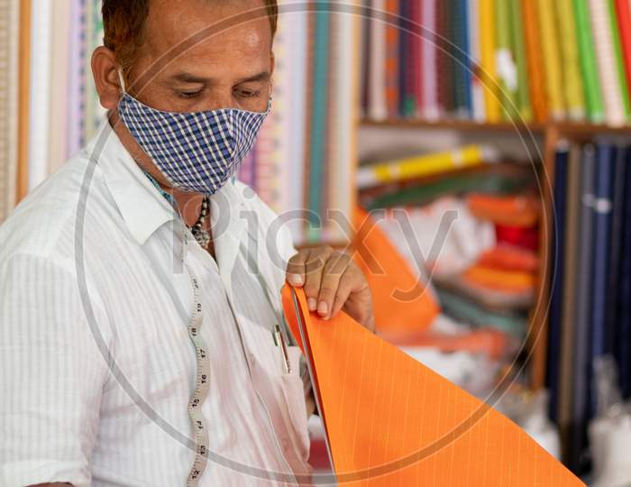 Shopkeeper In Medical Mask Measuring Cloth Using Scale Or Ruler - Concept Of Back To Business, Business Reopen After Covid-19 Or Coronavirus Pandemic.