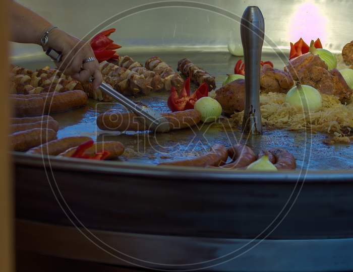 Gdansk, North Poland: Close Up Of A Food Such As Meat, Potatoes, Sausage And Onion Being Cooked On Big Pan In A Street Food Market Located In The Main Square City Center