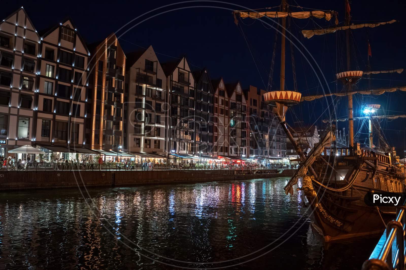 Gdansk, North Poland - August 13, 2020: Night Photograph Of Medieval Style Polish Architecture And A Pirate Ship Over Motlawa River Located In The Old Town Near Baltic Sea