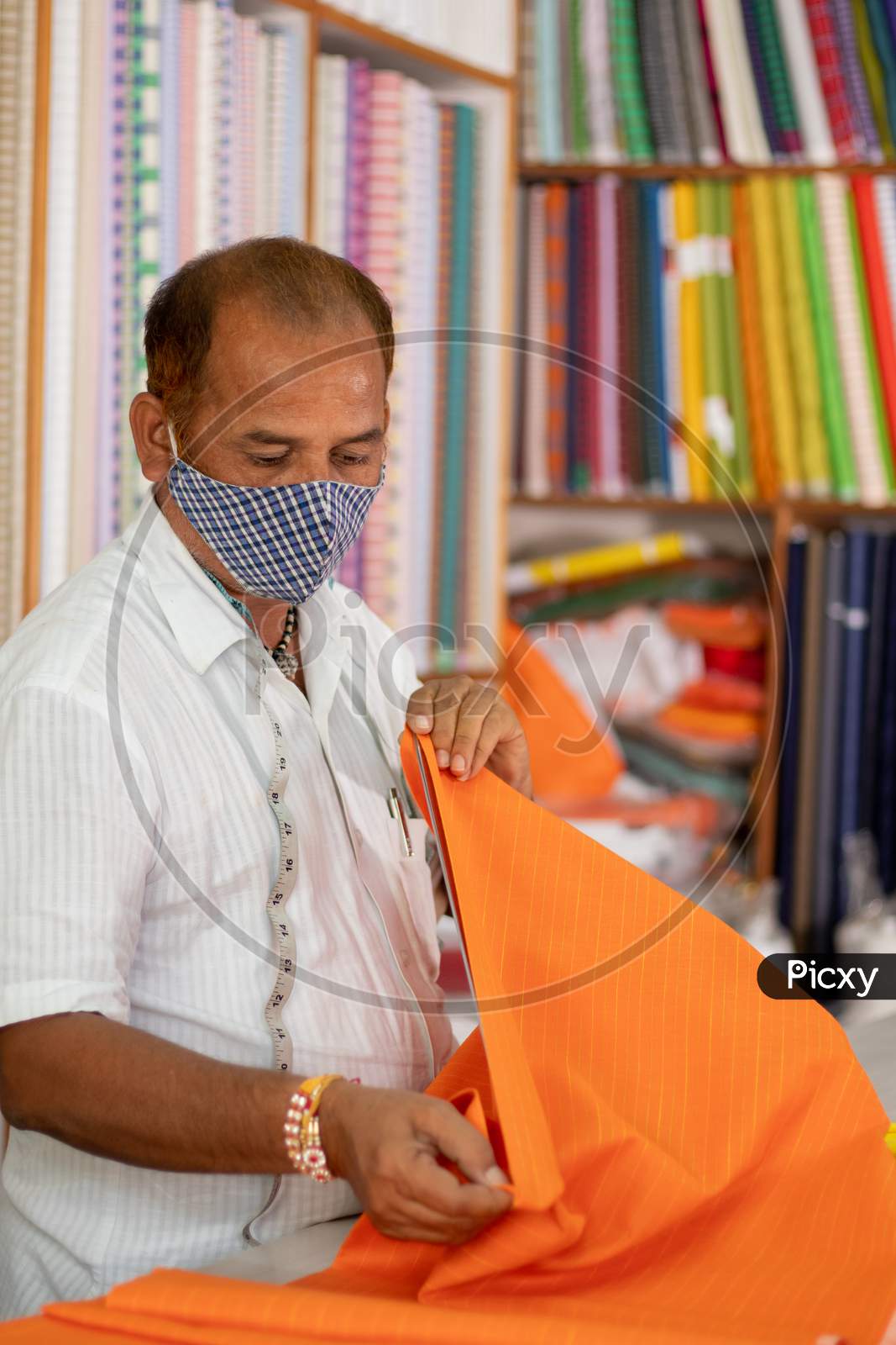 Shopkeeper In Medical Mask Measuring Cloth Using Scale Or Ruler - Concept Of Back To Business, Business Reopen After Covid-19 Or Coronavirus Pandemic.
