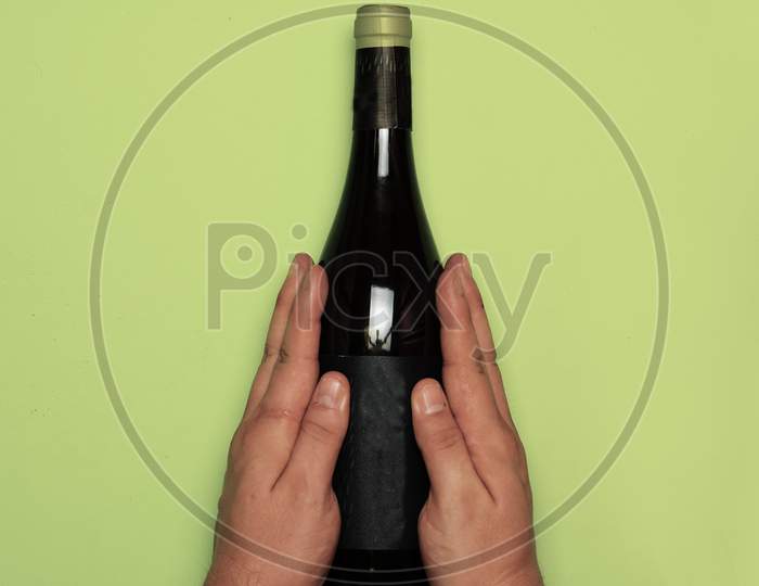 Man Hands Grabbing A Bottle Of Wine On Green Background. Flat Lay