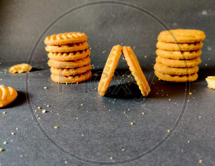 Stack Of Cashew Cookies Or Biscuits And Crushed Cookies Isolated On Black Background.Front View