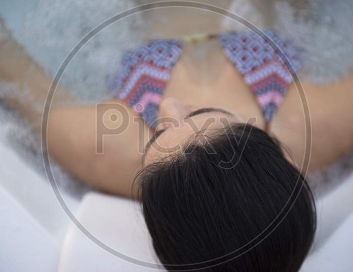 Top View Of Beautiful Bikini Woman In A Hydromassage Bath, , In A Bathing Suit. Concept: Spa Procedures, Body Massages, Spa Cream, Relax, Spa Water Treatments, Swimming Pool.