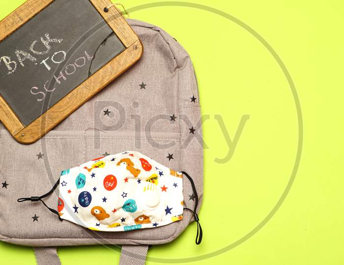 Top View Of Blackboard With Back To School Message On Backpack And Boy Or Girl Mask. Covid 19. Flat Lay Flat Design