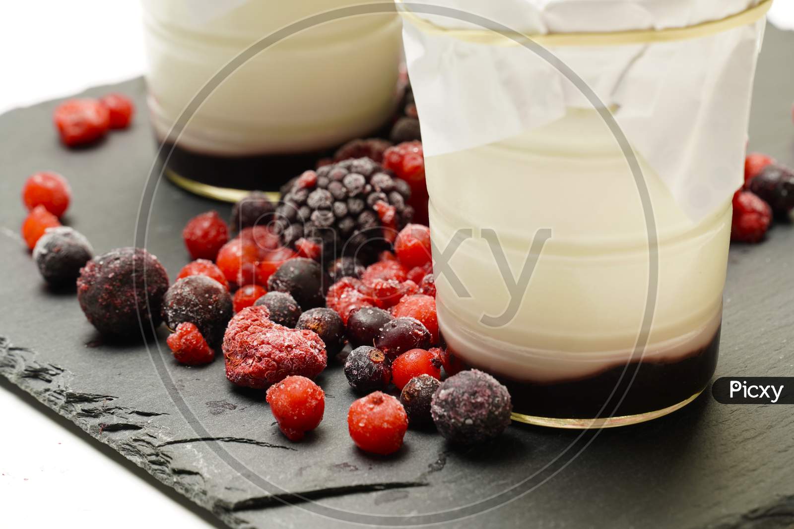 Organic Homemade Yogurts Surrounded By Blackberries And Gorse Fruits On A Black Slate Background. Gastronomy. Flat Lay