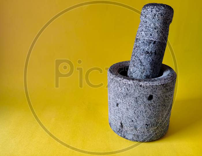 Mortar And Pestle Set Made Of Stone. Isolated On Yellow Background. Copy Space