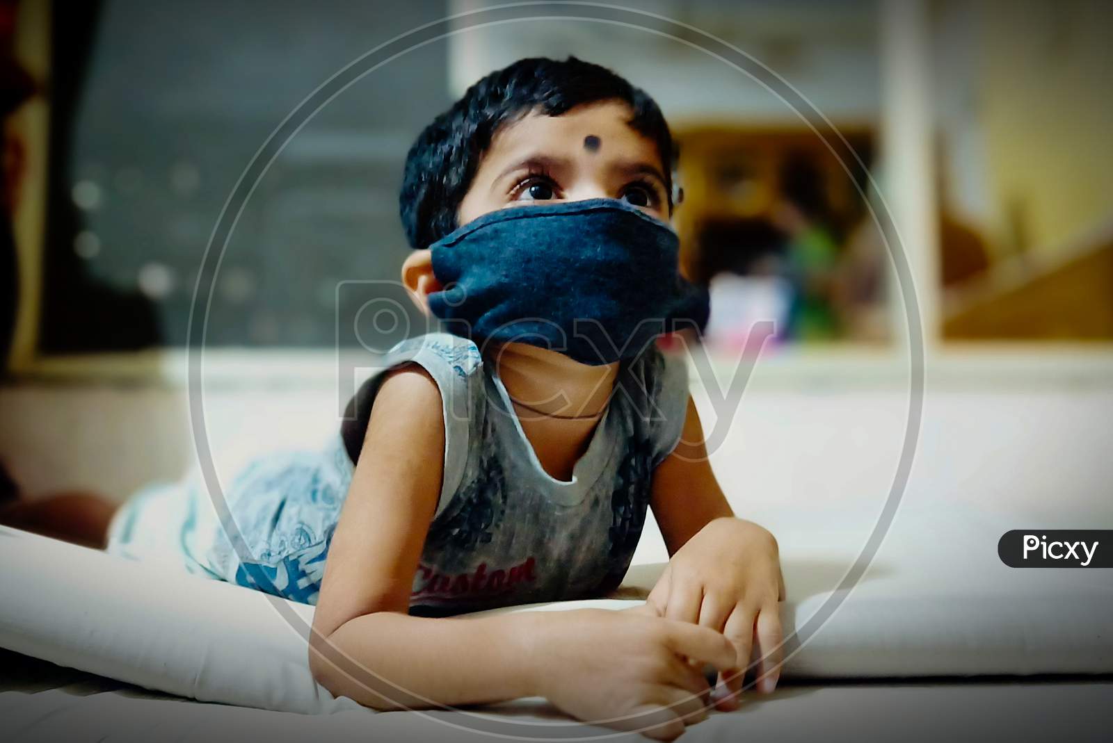 A child is  wearing the mask and watch the TV