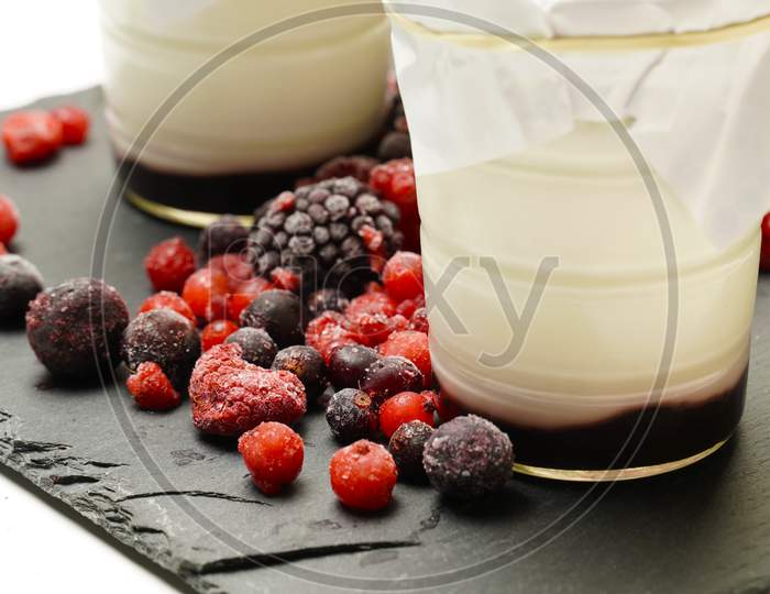 Organic Homemade Yogurts Surrounded By Blackberries And Gorse Fruits On A Black Slate Background. Gastronomy. Flat Lay