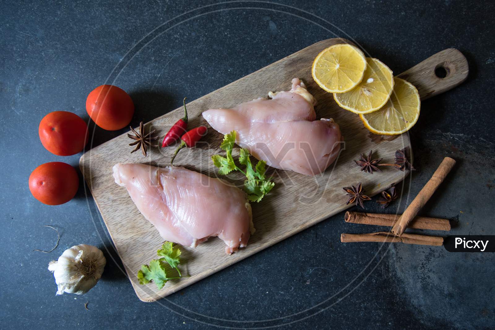 Top view of raw chicken breast on a wooden cutting board