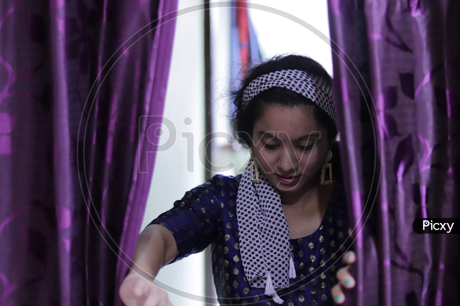 portrait of beautiful indian young woman, opeing purple curtain