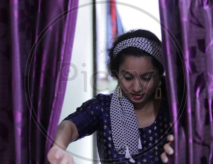 portrait of beautiful indian young woman, opeing purple curtain