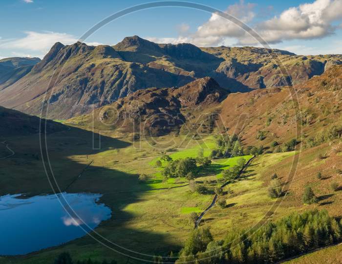 Blea Tarn Aerial Passover Which Shows The Tarn And Surrounding Area Including, Side Pike And Harrison Stickle, Thorn Crag, Blea Rigg And The Langdale Fells, In The English Lake District.Uk