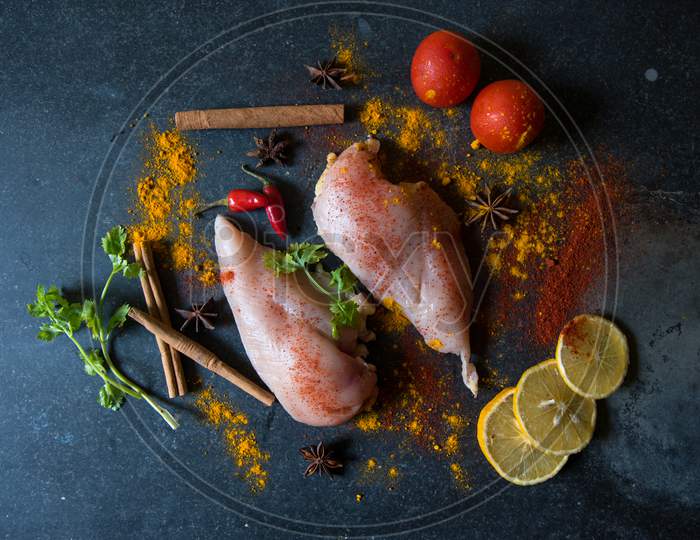 Raw chicken breast fillets with vegetables and spices