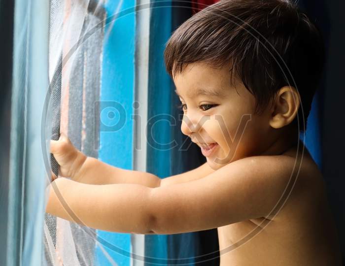 close up of indian baby boy standgin at window