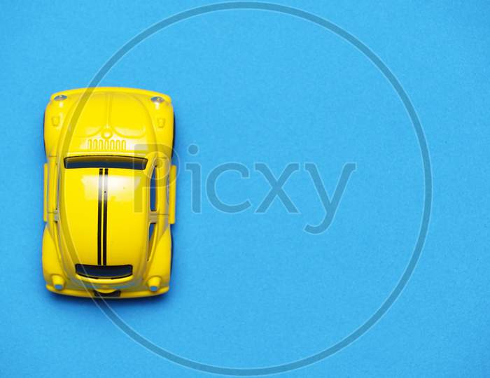 Top View Of Yellow Car On Blue Background. Car Travel Concept. Flat Lay