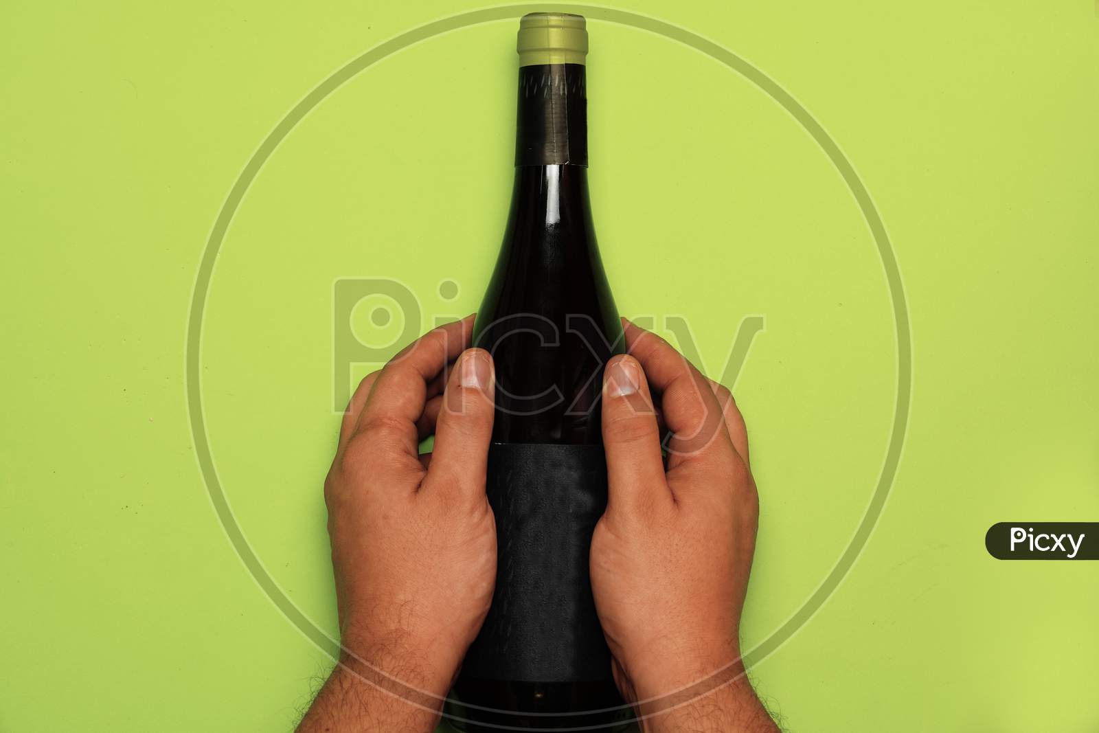 Man Hands Grabbing A Bottle Of Wine On Green Background. Flat Lay .