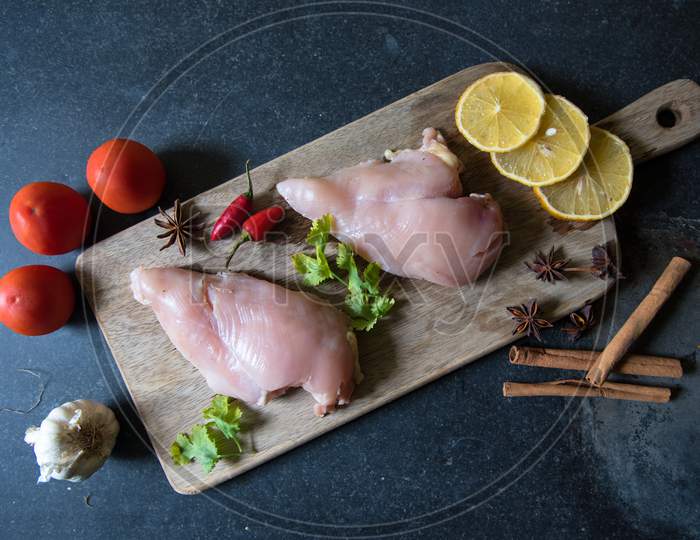 Top view of raw chicken breast on a wooden cutting board