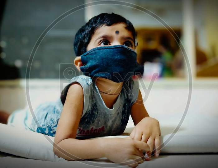 A child is  wearing the mask and watch the TV