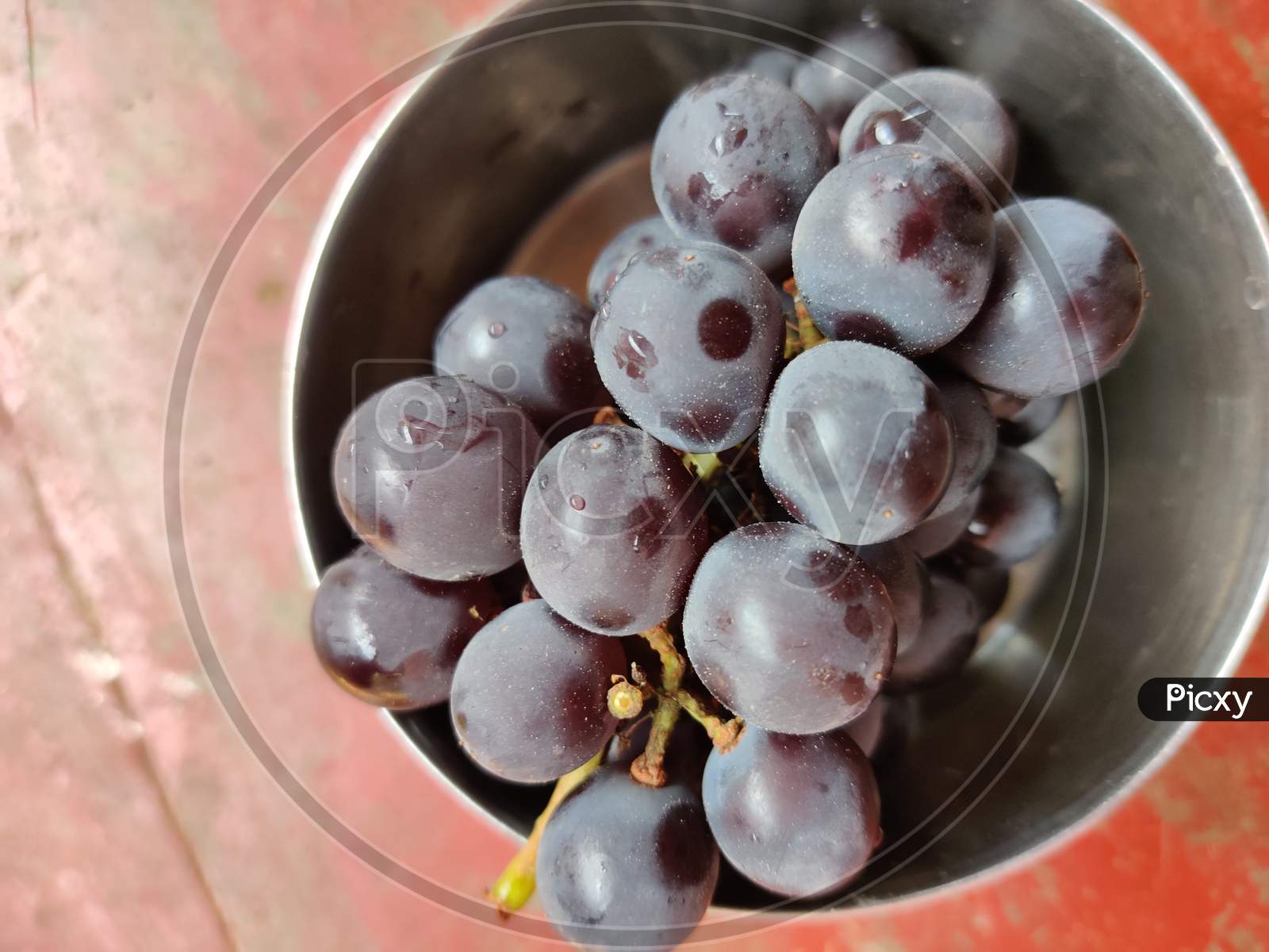 A bunch black Indian grapes kept in steel bowl.