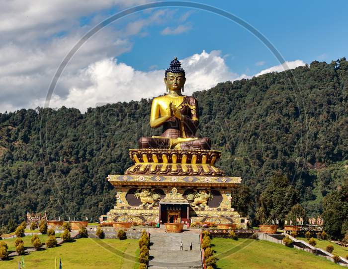 The statue of Buddha at the Buddha park with blue sky and clouds in the background