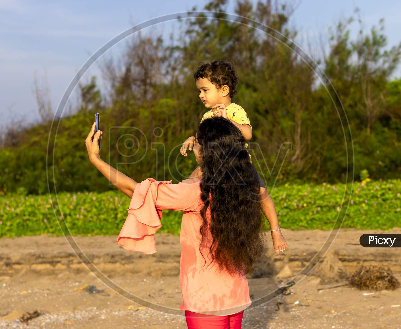 An Asian Mother Seated Her Child On Her Shoulder And Took A Selfie With A Smartphone