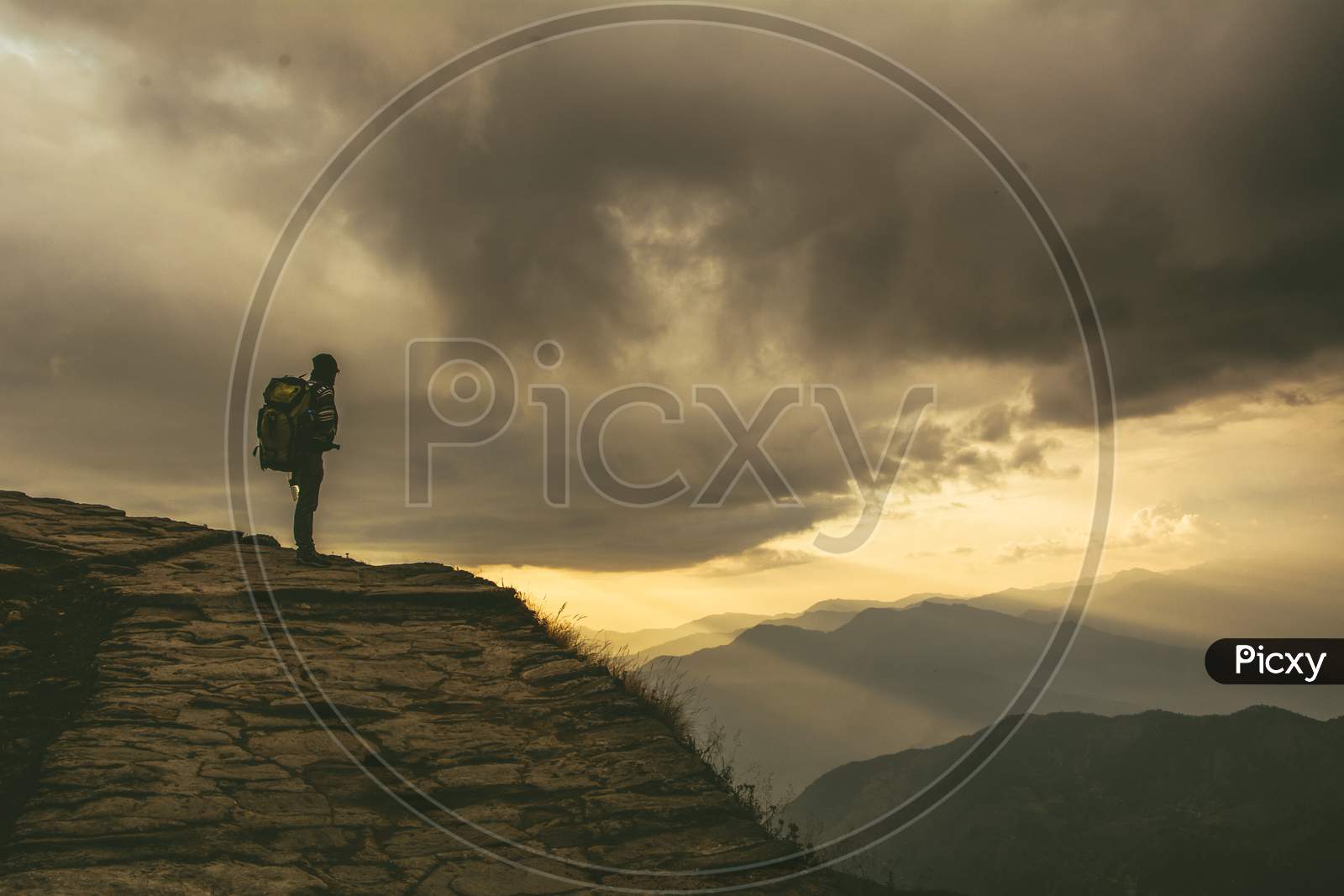 A solo mountain traveller enthralled by the beauty of light coming trough the black cloud