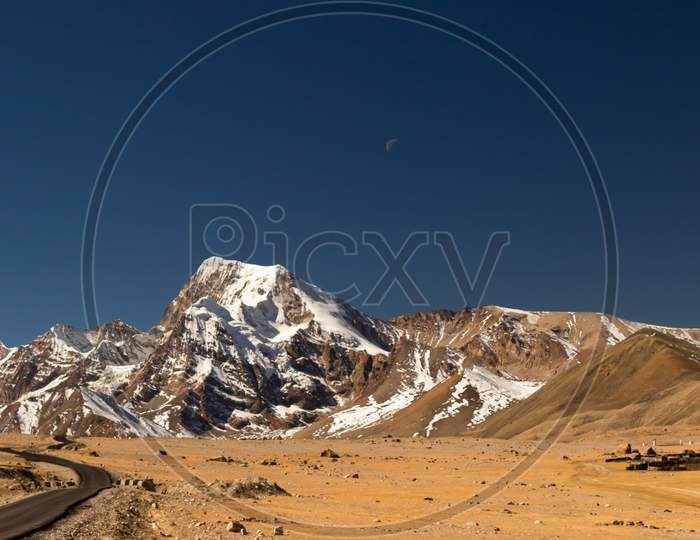 A long lonely road with curves on the tibetan plateau with snow clad mountainsA long lonely road with curves on the tibetan plateau with snow clad mountains