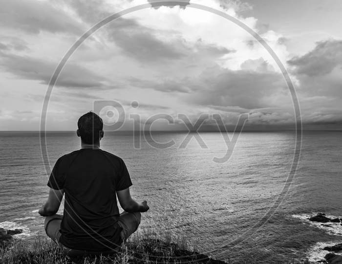 Man Meditating At Hilltop With Amazing Landscape And Sea Horizon At Morning