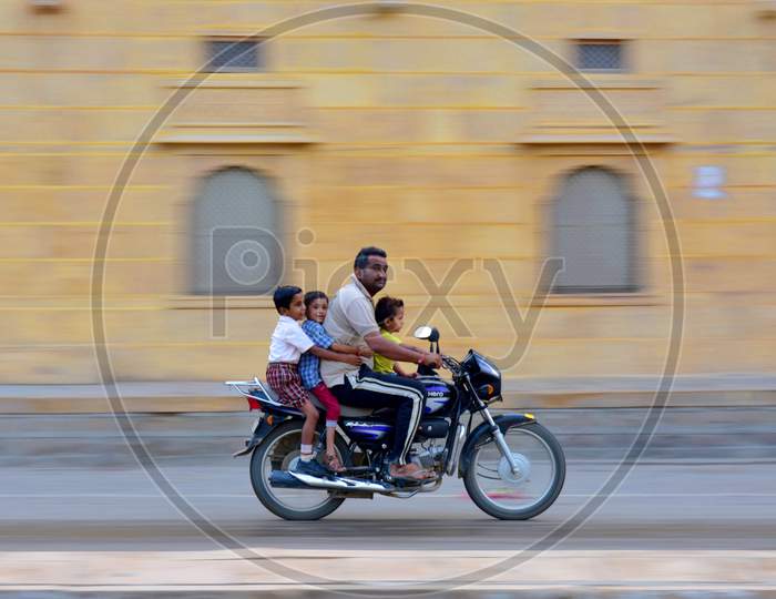 A man with three children on his bike heading towards their school
