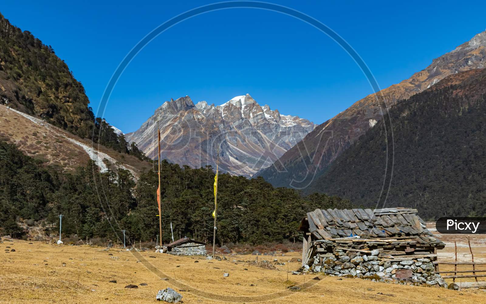 image of a hut made of stones with Tibetan prayer flags in front