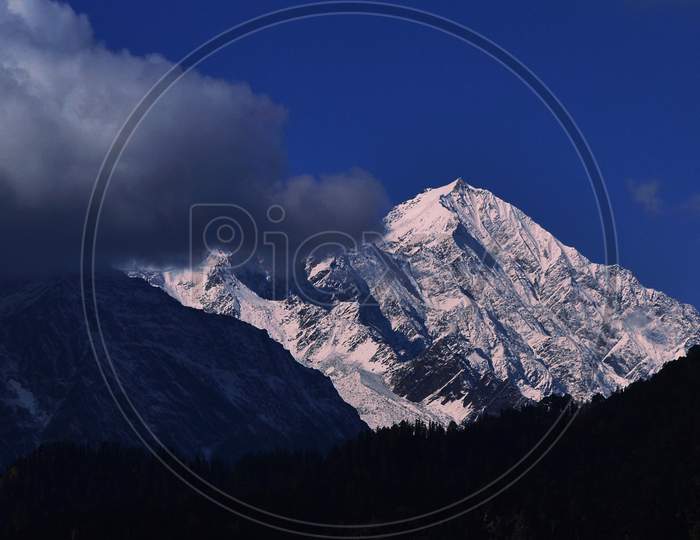A Snow Capped Mountain with a Piece of Floating Cloud in it's Foreground