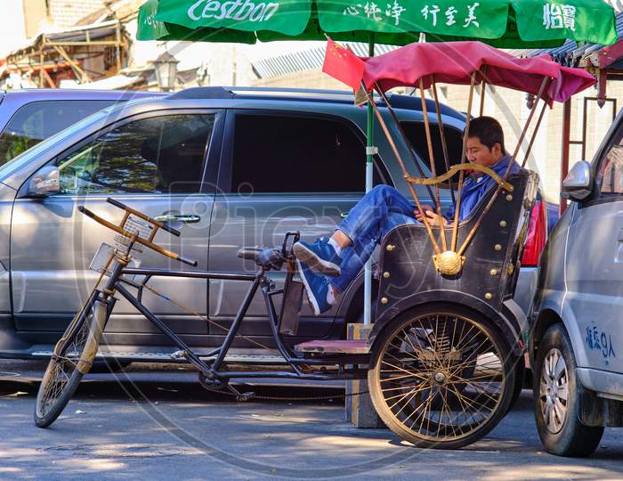 Tourist Bicycle Rickshaw Driver Taking A Break From Work In Beijing, China