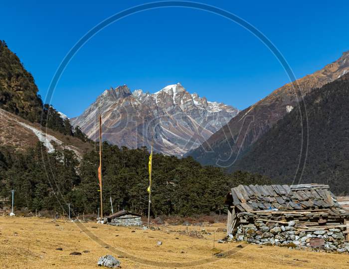 image of a hut made of stones with Tibetan prayer flags in front