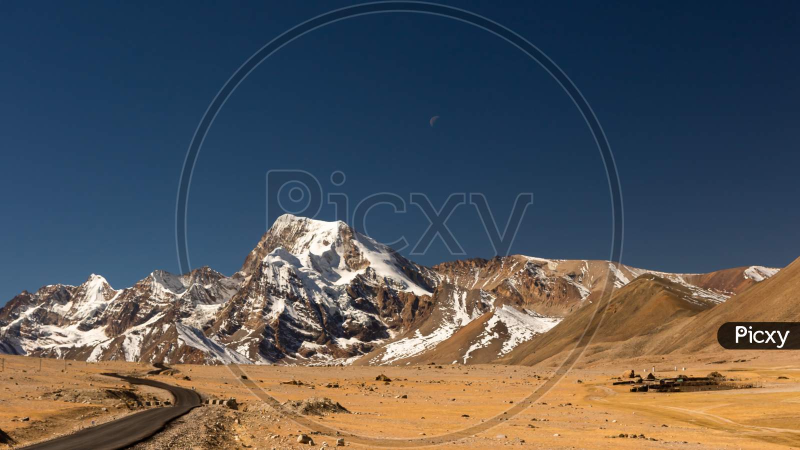 A long lonely road with curves on the tibetan plateau with snow clad mountainsA long lonely road with curves on the tibetan plateau with snow clad mountains