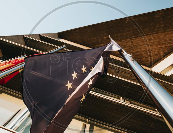 Close Up Of The European Flag Waving Surrounded By Other Flags In Front Of A Governmental Building