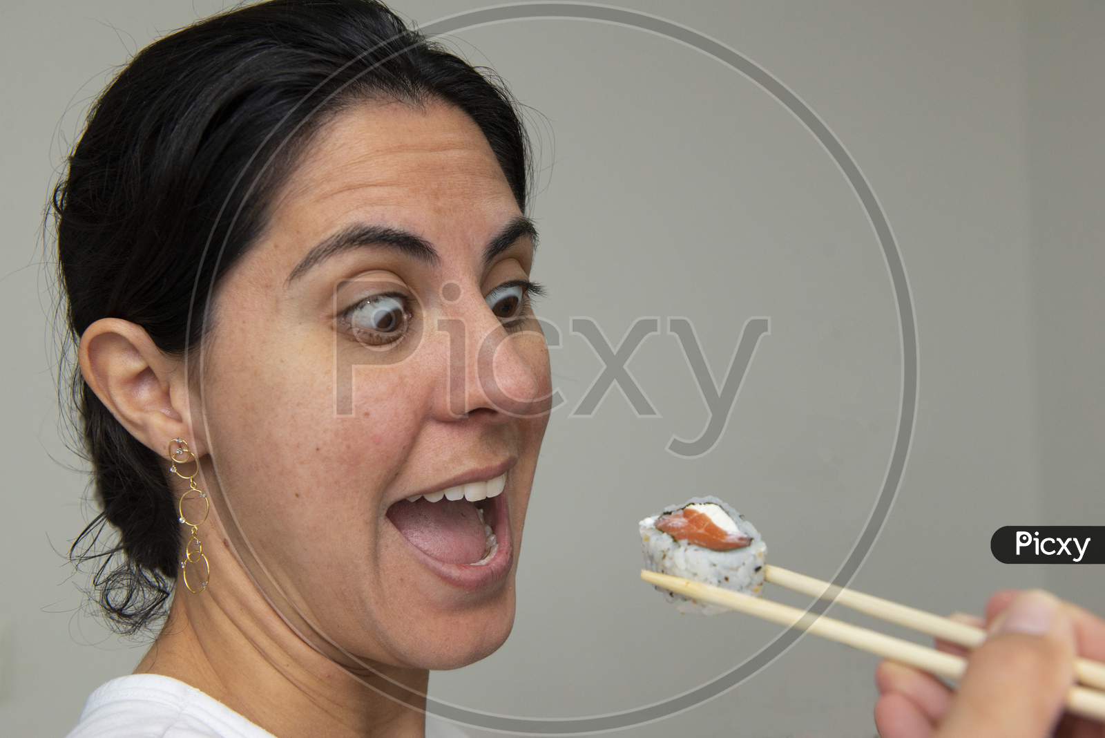 Pretty Woman Eats Rolls With Chopsticks Sushi On Grey Background