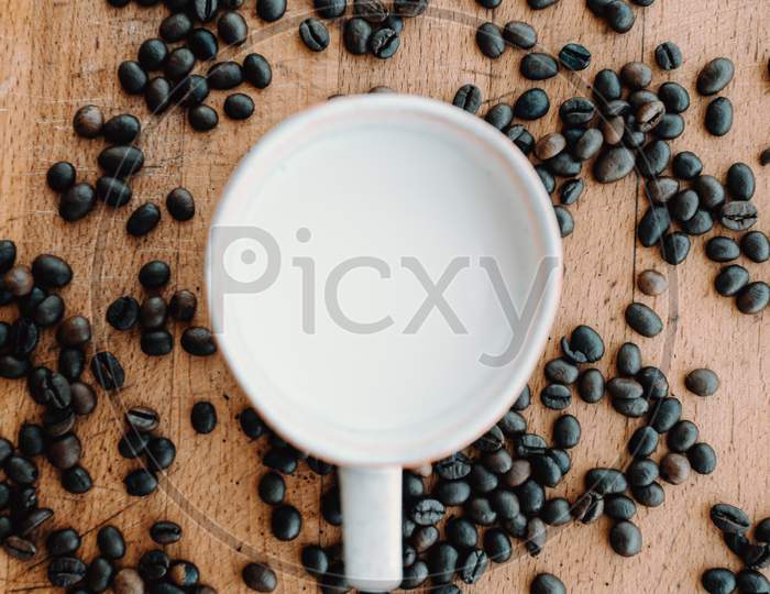 Close Up Flat Lay Of A Cup Of Milk Surrounded By Coffee Grains