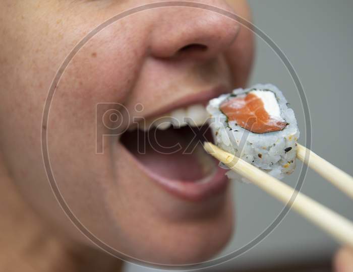Close Up Of Woman'S Mouth Eating Delicious Salmon Sushi (Uramaki).