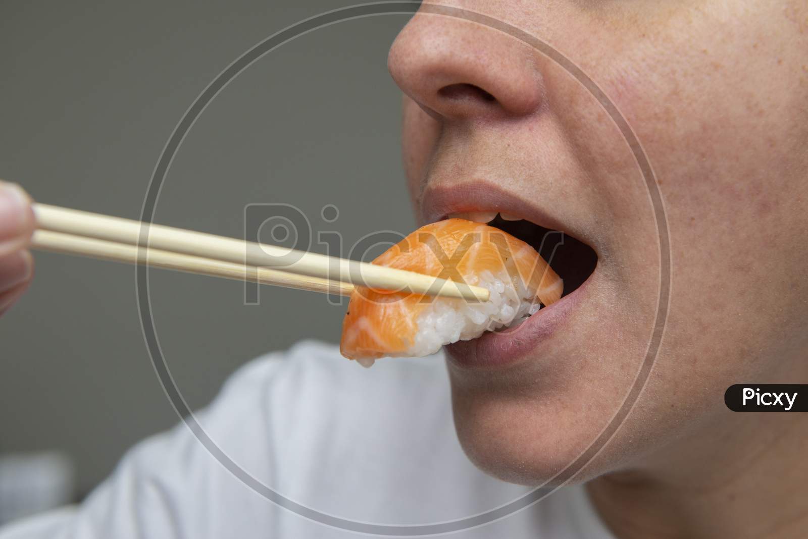 Close Up Of Woman'S Mouth Eating Delicious Salmon Sushi (Niguiri).