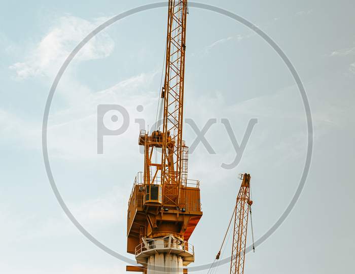 Minimal Shot Of Two Yellow Industrial Cranes With A The Blue Sky As The Background