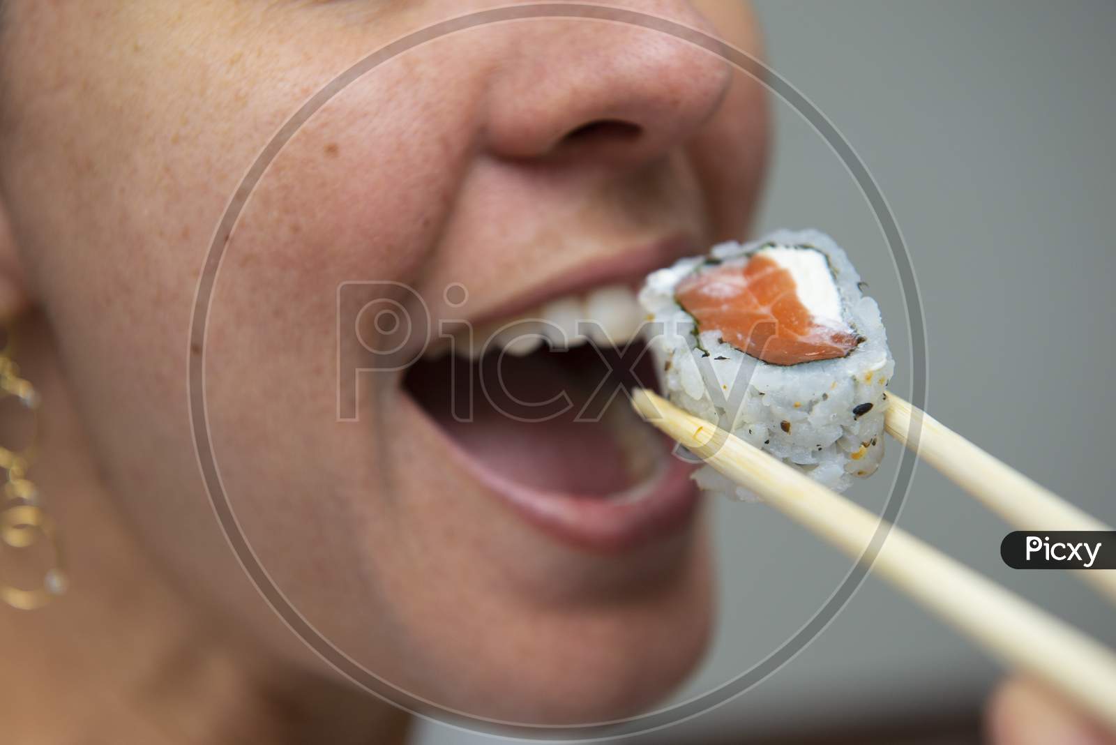 Close Up Of Woman'S Mouth Eating Delicious Salmon Sushi (Uramaki).