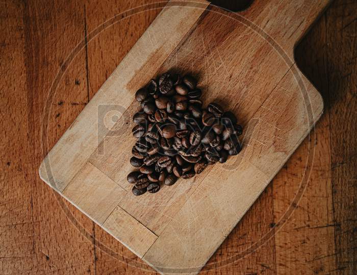 A Flat Lay Of A Heart Symbol Made Of Coffee Grains Over Two Wood Tables