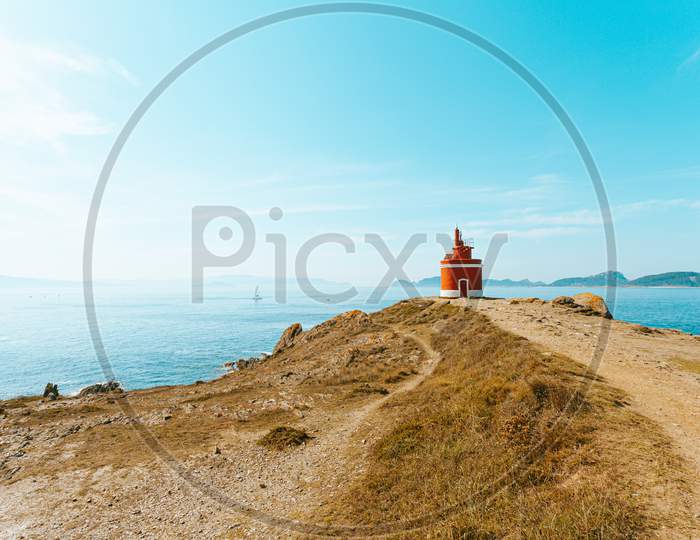 Colorful Shot Of A Red Lighthouse In The Front Of The Ocean With Islands In The Horizon With Copy Space