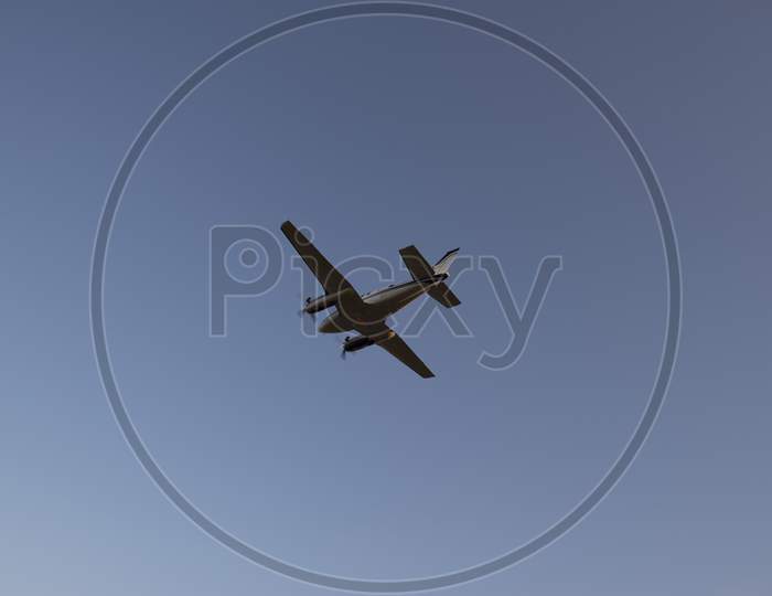 Bottom View Of Propeller-Powered Airplane Taking Off From The Airport During Sunset