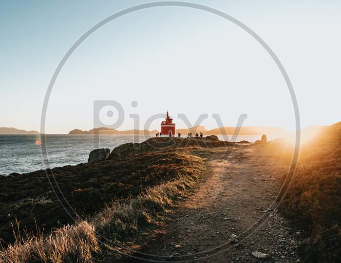 Path To The Red Lighthouse Under A Massive Sunset In The Coastline Of Spain During A Super Bright Day