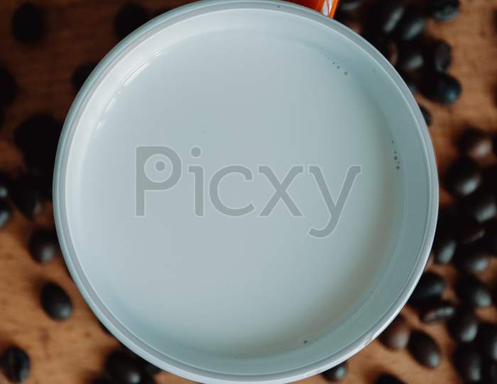 Super Close Up Flat Lay Of A Cup Of Milk Surrounded By Coffee Grains