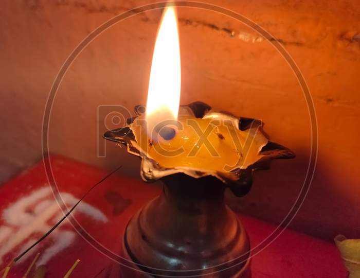 A Silver Oil Lamp With Flame.