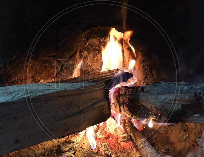 Traditional way of making food by using fire wood as bio fuel on open fire in old kitchen in a village. Rural kitchen using bio wood fuel for cooking.